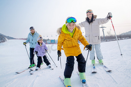 儿童拿的动作摄影照片_滑雪场内滑雪的一家四口