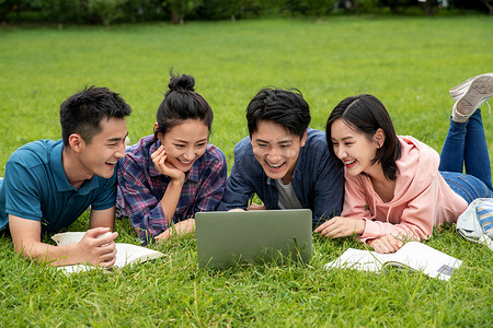 学生趴摄影照片_快乐的大学生趴在草地上学习