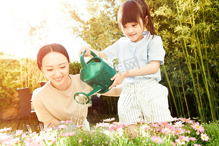 花北京摄影照片_年轻的母亲和女儿在浇花