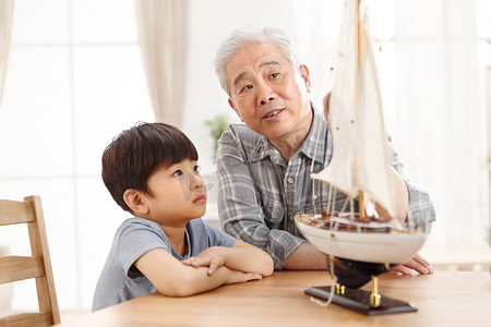 玩具帆船摄影照片_祖父和孙子在客厅玩耍