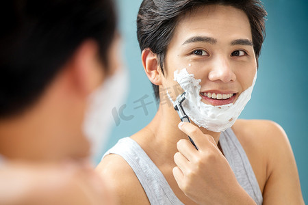 青年男人对着镜子刮胡子