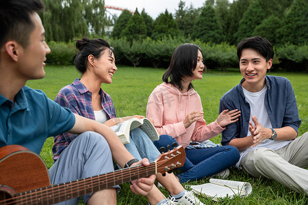 快乐的大学生在草地上弹吉他唱歌