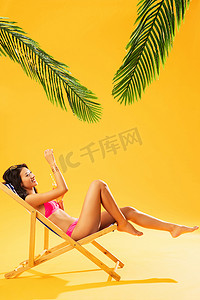 沙滩晒太阳摄影照片_在躺椅上晒太阳的比基尼美女