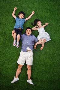 儿童托举摄影照片_在草地上父亲托举儿子和女儿