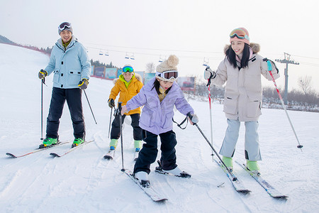 冬季亲情摄影照片_滑雪场内滑雪的年轻家庭