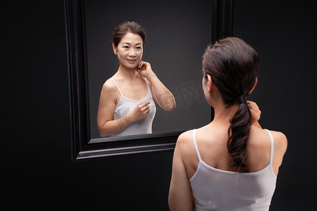 中年女性欣赏镜子中的自己