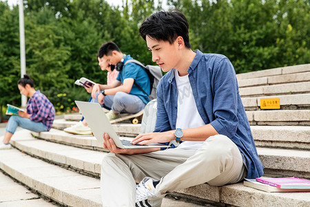 绿色校园摄影照片_快乐的大学生坐在台阶上学习