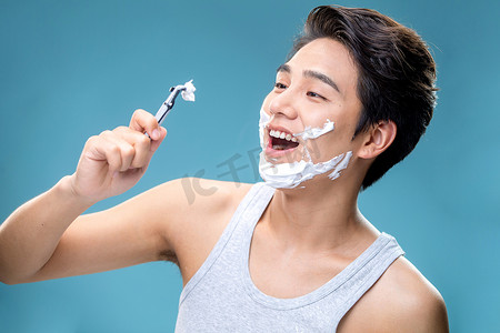 刮胡刀海报摄影照片_帅气的年轻男人刮胡子
