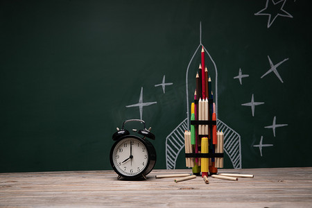 彩色铅笔素材摄影照片_文具创意火箭和桌子上的闹钟