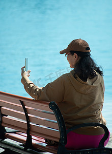 昆明湖摄影照片_皇家园林颐和园昆明湖湖边长椅拍照的人