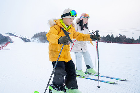 雪地玩耍人物摄影照片_快乐母子在滑雪场一起滑雪