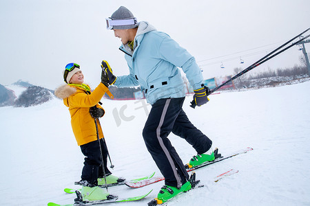 滑雪场上滑着雪击掌的快乐父子