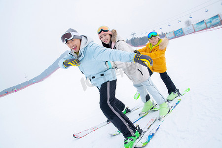 冬季亲情摄影照片_滑雪场上踩着滑雪板排队行走的一家三口