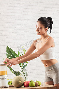 水果新鲜不新鲜摄影照片_健康女人使用榨汁机