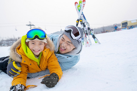 滑雪场内抱在一起打滚的快乐父子