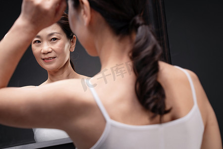 中年女性欣赏镜子中的自己