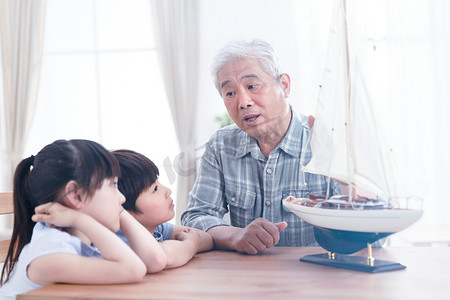 玩具帆船摄影照片_祖父陪孙辈在客厅玩耍