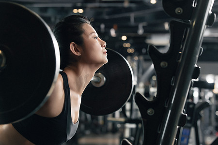 年轻女子在健身房练习抗杠铃