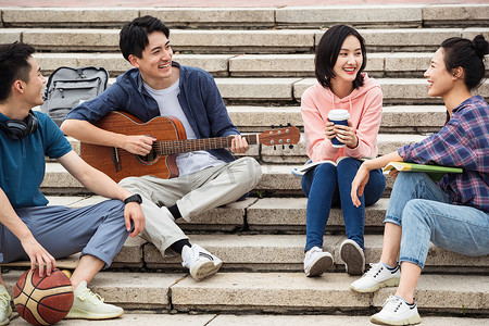 年轻的大学生坐在台阶上弹吉他