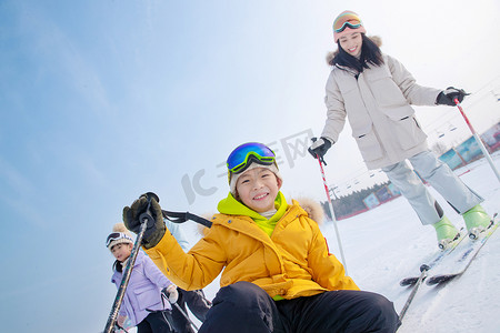 蓝天雪地摄影照片_滑雪场内边滑雪边嬉戏的一家四口