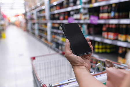 中年女性拿着手机在超市购物
