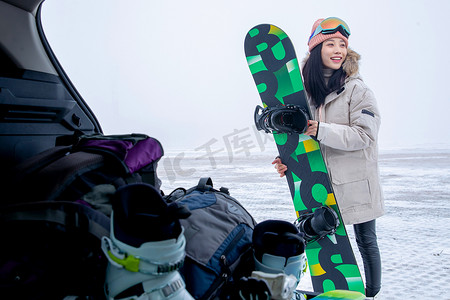 青年女人从后备箱拿单板滑雪板