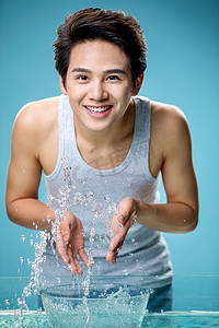 蓝色透明水珠摄影照片_帅气的年轻男人洗脸