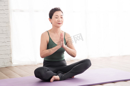 清新运动减肥健身摄影照片_室内坐着练习瑜伽的中老年女士