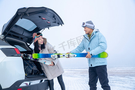 滑完雪的青年伴侣往汽车后备箱里装滑雪板