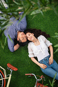甜蜜相伴摄影照片_甜蜜的青年伴侣躺在草地上
