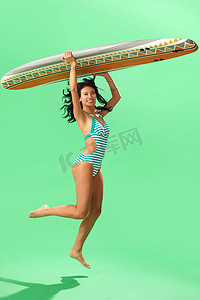 清爽一夏天摄影照片_穿泳装的美女举着冲浪板跳跃