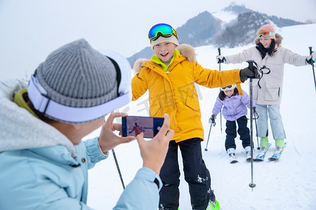 滑手机屏幕摄影照片_滑雪场上父亲用手机给孩子们和妻子拍照