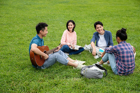 快乐的大学生在草地上弹吉他唱歌