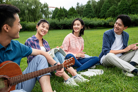 快乐的大学生在草地上弹吉他唱歌