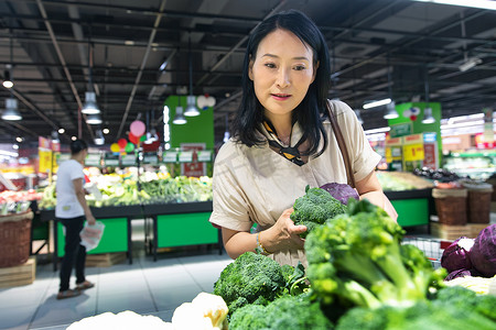 中年女性在超市挑选蔬菜