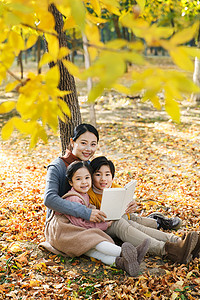 树下看书的女生摄影照片_妈妈和孩子在树下看书