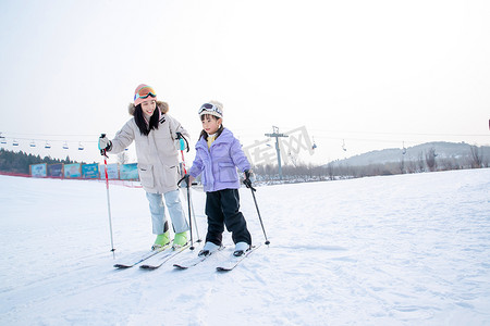 冬天帽子手套摄影照片_滑雪场上滑雪的快乐母女