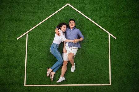 青年伴侣躺在草地上的房子轮廓里
