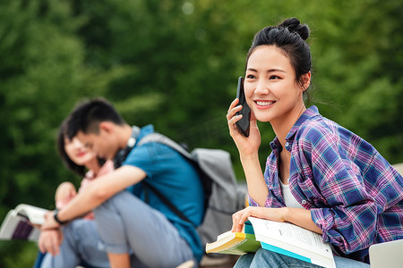 绿色校园摄影照片_快乐的大学生坐在台阶上打电话