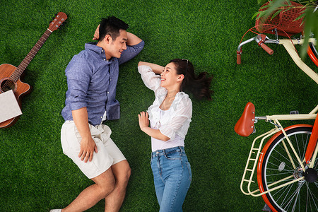 幸福的青年伴侣躺在草地上享受甜蜜时光