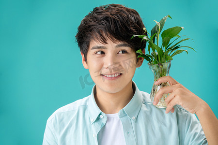 植物造型图片摄影照片_拿着绿色植物的青年男人