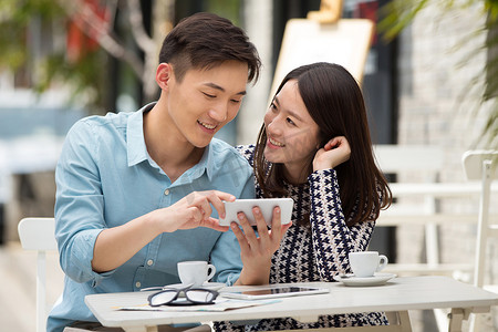 微信表情发摄影照片_青年情侣坐在咖啡馆看手机