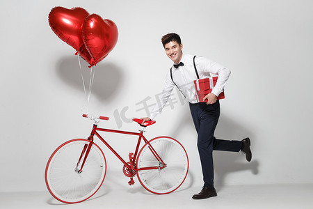 浪漫气球礼物摄影照片_青年男人推着自行车跑
