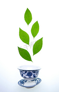 青花瓷茶杯摄影照片_绿色的茶叶和茶杯