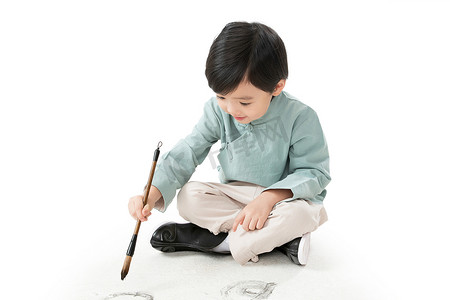 南宁书法字体摄影照片_小男孩盘腿坐着拿毛笔写字