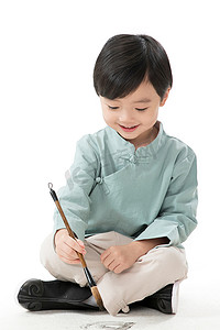 学习知识教育元素摄影照片_可爱的小男孩坐在地上用毛笔写字