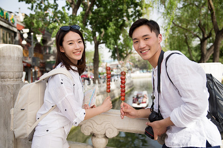 北京特产糖葫芦摄影照片_青年情侣旅游拿着糖葫芦