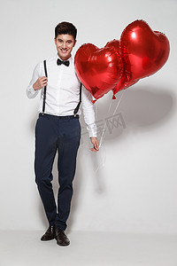 浪漫气球礼物摄影照片_青年男人拿着心形气球
