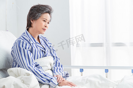 古人枕头摄影照片_老年患者坐在医院病床上