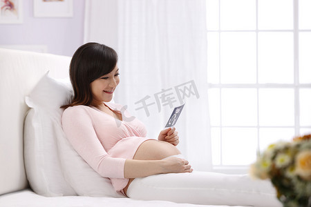 孕妇坐在床上看超声波照片